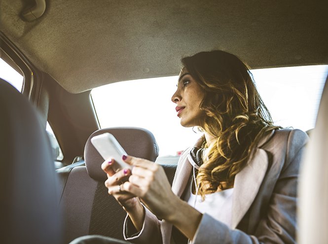 девушка сидит в машине uber яндекс такси - красивая женщина с телефоном в руках