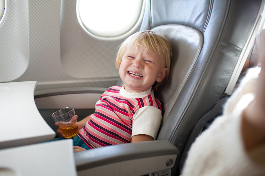 ребенок кричит и плачет в самолете - орущий мальчик пьет сок на борту