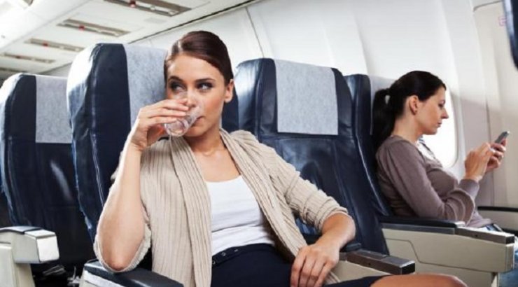 красивая женщина в самолете - девушка пьет воду на месте у прохода на борту