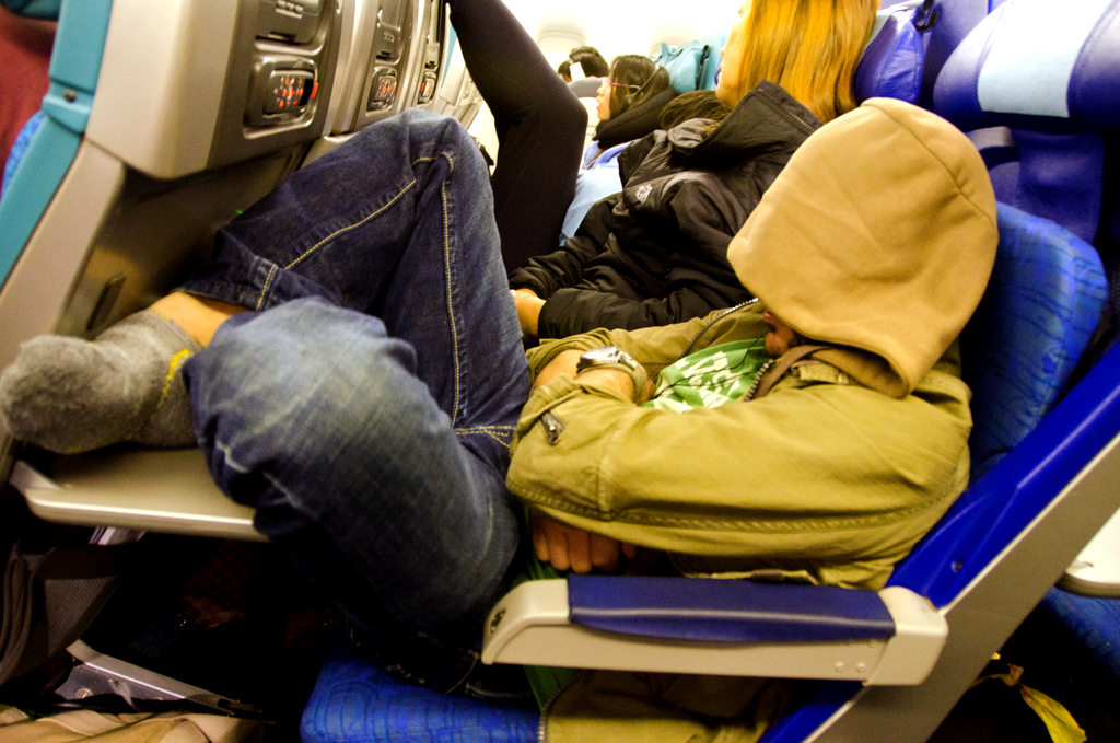 парень спит в самолете в кресле у прохода
